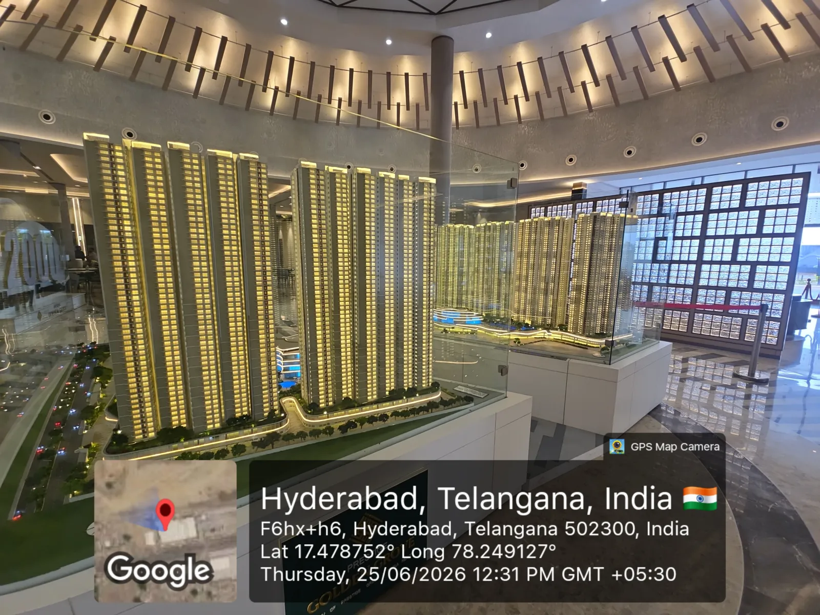 Prestige Golden Grove Scale Model — Tower Elevation (Experience Centre, June 2026) Side elevation of the Prestige Golden Grove scale model showing the full height of the residential towers beside the floor-plan display panels at the experience centre, Hyderabad, June 2026.