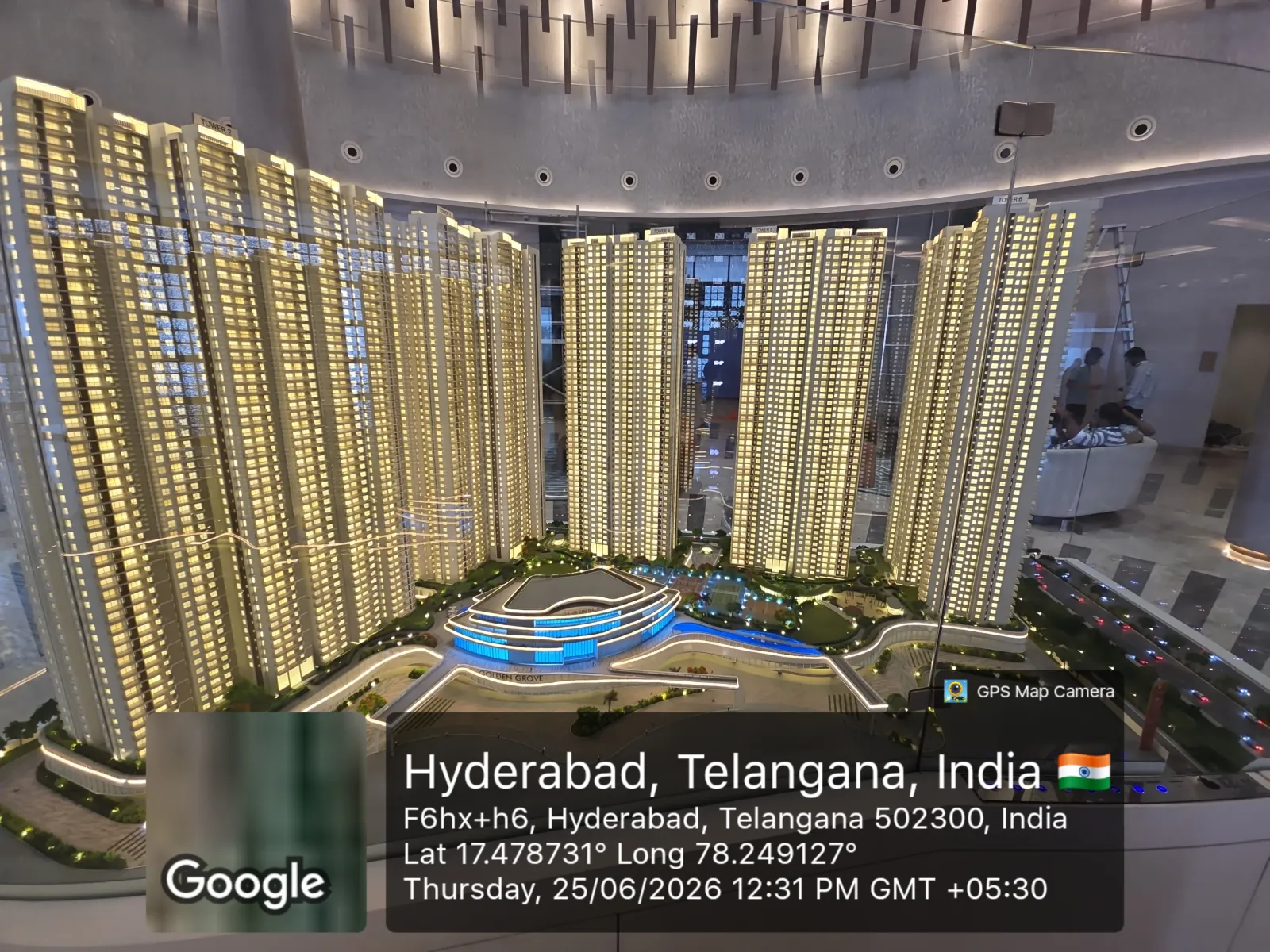 Prestige Golden Grove Scale Model — Towers & Central Clubhouse (Experience Centre, June 2026) Illuminated scale model of the Prestige Golden Grove towers arranged around the central clubhouse and pool, on display at the on-site experience centre, Velimela, Hyderabad, June 2026.